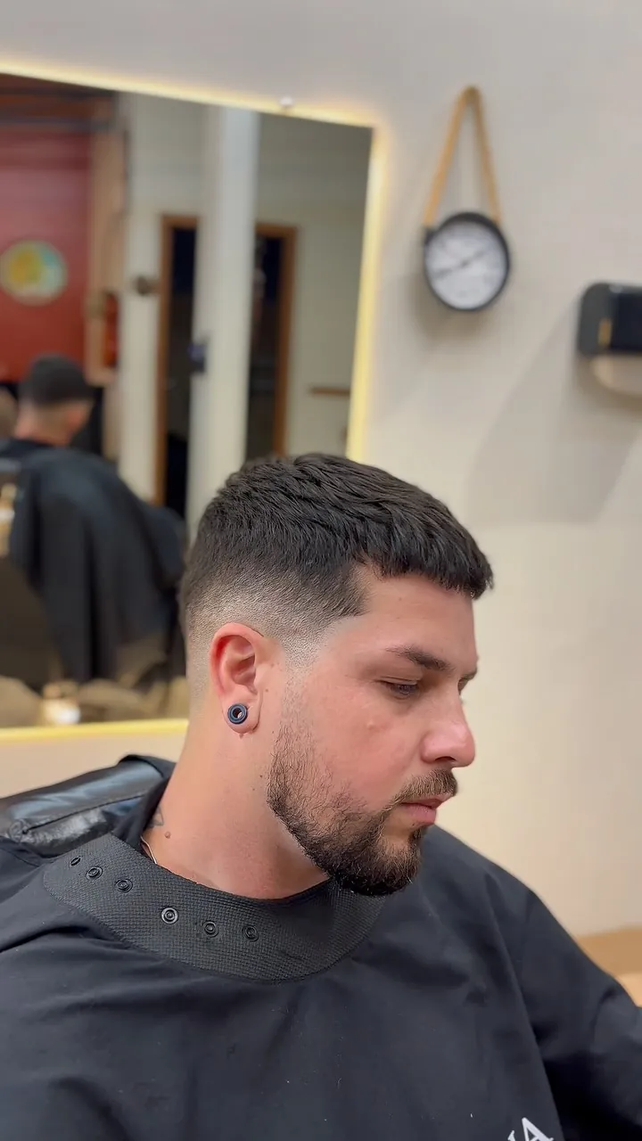 Corte texturizado com o espelho iluminado da barbearia ao fundo